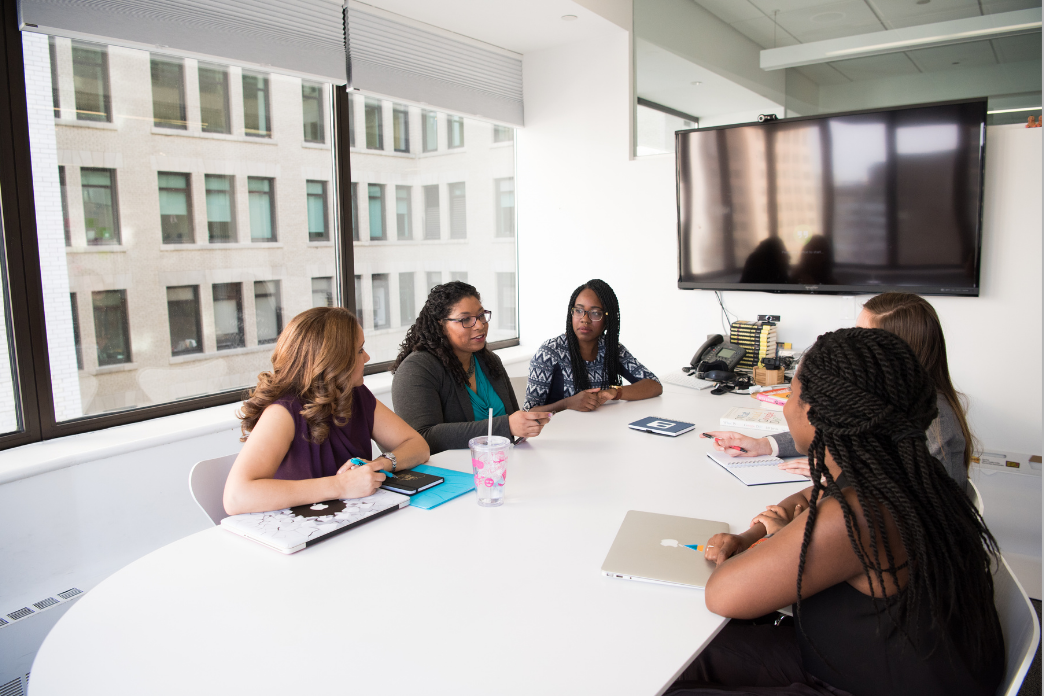 Black business women gather around a conference room table