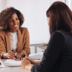 African American business woman smiling while reviewing information with client