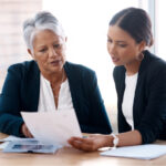 Older woman and younger woman in business attire reviewing documents