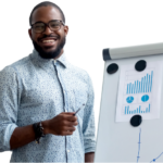 Young African American man with glasses and light blue shirt presenting graphs on a whiteboard